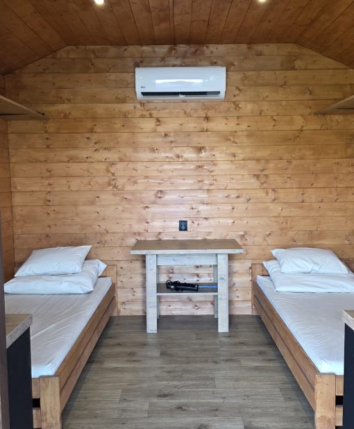 Wnętrze domku na stanowisku 3 – klimatyzacja nad stolikiem między łóżkami